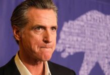Gavin Newsom at a press event with a purple backdrop