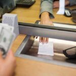 Bank teller hands receipt through service window