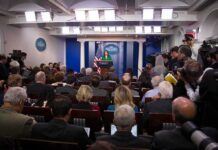 Five-Day Tenure Shakes Up White House Press Office Press secretary at podium addressing reporters in briefing room